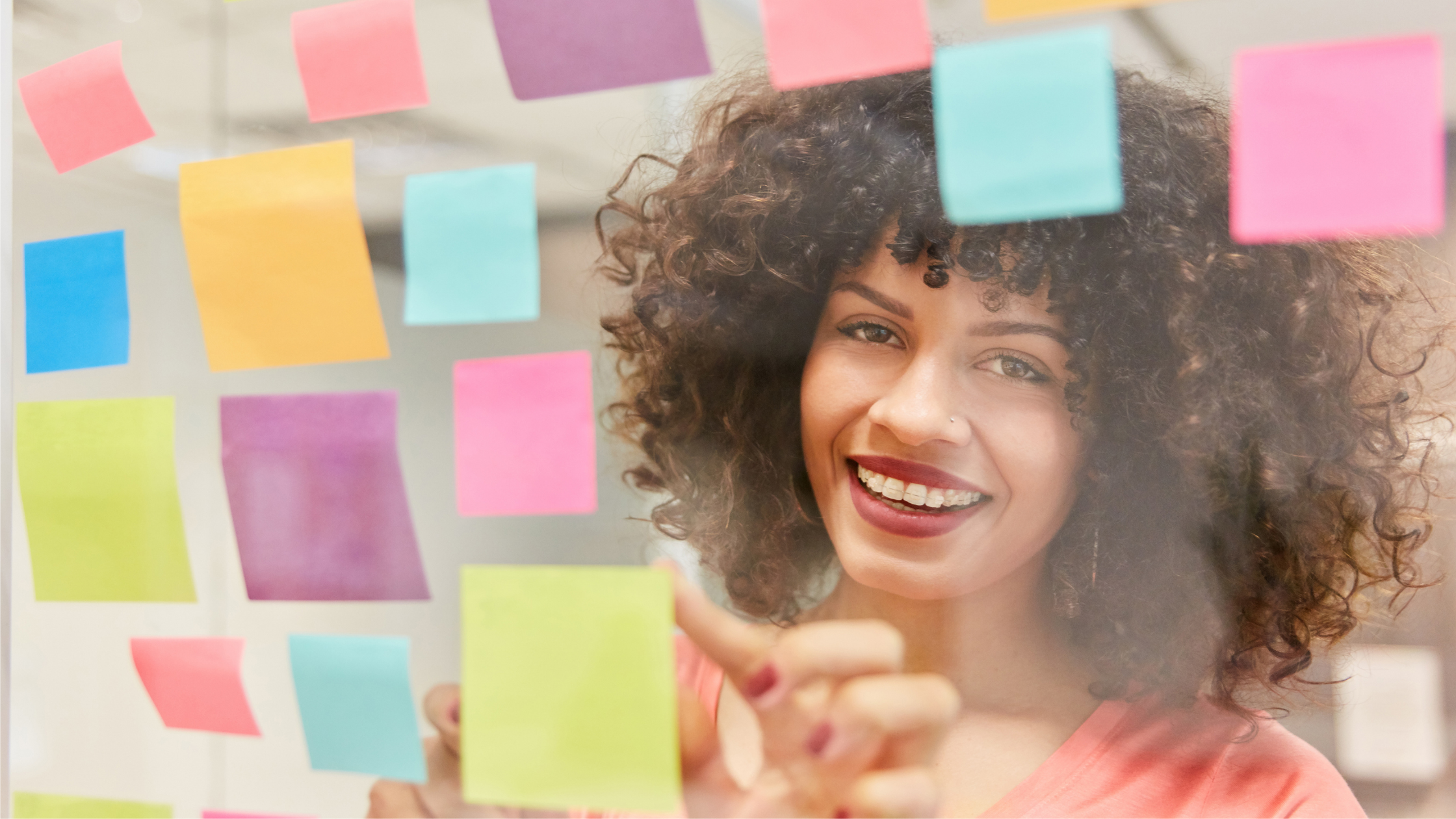 Afro american woman with curly hair writes about employer branding on sticker notes with confidence